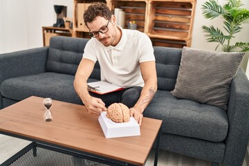 Young hispanic man psychology holding brain at psychology center