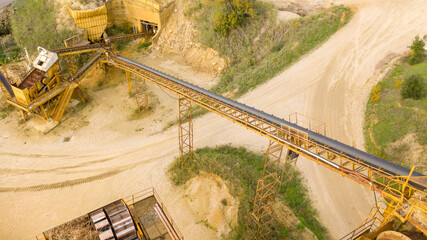 Aerial view on the rubber conveyor belt of an industrial tool. Aggregate crushing and sorting plant. Industry closeup.