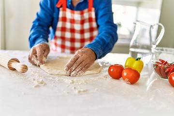 Senior man keading dough with hands at kitchen