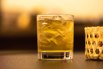 A glass of whisky and ice on table with blur background.