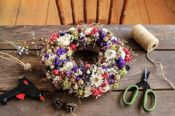 Woman shows how to make a door wreath with dry flowers and orher plants. Step by step, tutorial.