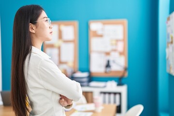 Young chinese woman business worker standing with arms crossed gesture at office