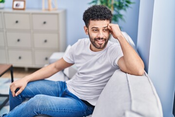 Young arab man smiling confident sitting on sofa at home