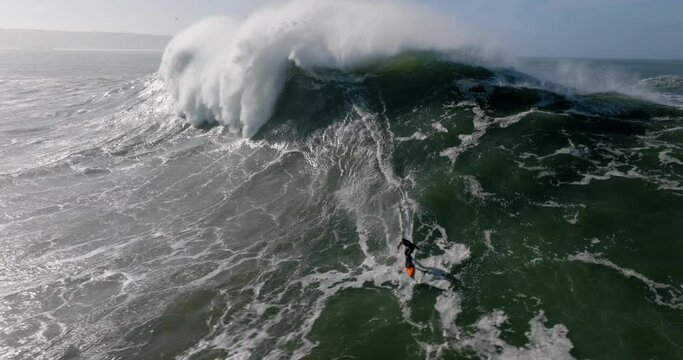 Aerial view of a professional big wave surfer on a big wave in Nazare surfing spot, Portugal. Jet ski surfing in Atlantic ocean.