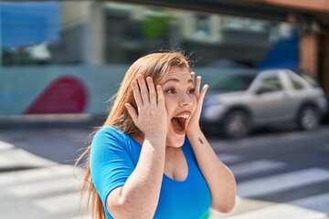 Fototapeta premium Young redhead woman standing with surprise expression at street