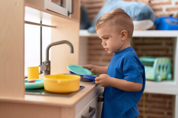 Adorable toddler playing with play kitchen standing at kindergarten