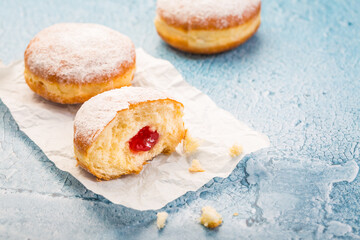 German donuts - berliner filled with strawberry jam with icing sugar