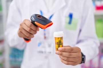 Young hispanic teenager pharmacist scanning pills bottle at pharmacy