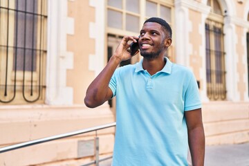 Young african american man smiling confident talking on the smartphone at street