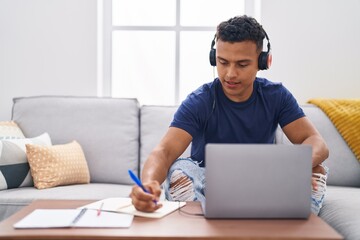 Young latin man sitting on sofa studying at home