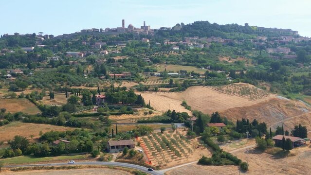 Aerial jib up revealing the town of Volterra, Italy. Roadside vineyards and city can be seen.