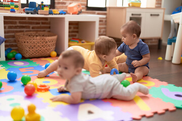 Fototapeta premium Group of toddlers playing with toys crawling on floor at kindergarten