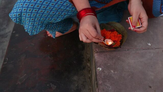 young girl devotee lighting oil lamps to offer holy river ganges at evening from top angle
