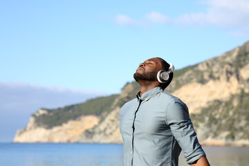 Black man meditating with headphones on the beach