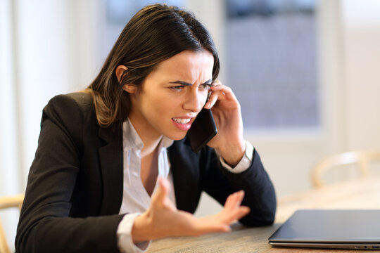 Angry businesswoman talking on phone at office