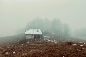Abandoned stone house in the mountain side on a misty winter day. - 553151593