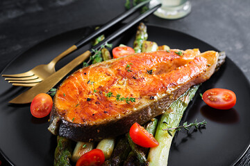 Roasted salmon garnished with asparagus and tomatoes with herbs. Ketogenic lunch. Keto diet