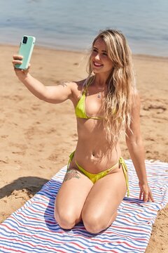 Young woman tourist wearing bikini making selfie by smartphone at seaside