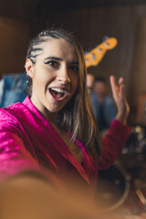 Fototapeta premium Excited stylish female vocalist takes a photo of herself during band practice. Musicians and recording studio concept. High quality photo