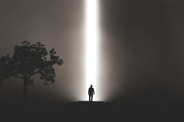 A silhouette of a man in nature next to a tree, walking towards a bright light in the opened huge wall. A light in the end of a tunnel. The concept of success, freedom, choice, open mind, meditation. - 553152709