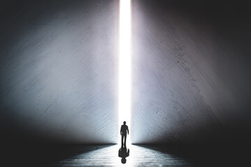 The silhouette of a man walking towards a bright light in the opened huge wall. A light in the end of a tunnel. The concept of success, freedom of choice, open mind, meditation. - 553152728