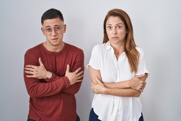 Mother and son standing together over isolated background shaking and freezing for winter cold with...