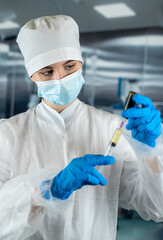 female doctor or assistant wearing blue uniform holding syringe with medicine in surgery room.