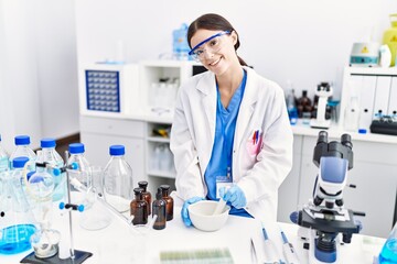 Young hispanic woman wearing scientist uniform working at laboratory