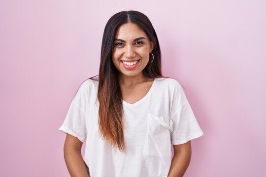 Young arab woman standing over pink background with a happy and cool smile on face. lucky person.