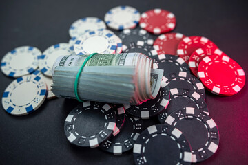 playing cards scattered with chips behind a roll of us dollars isolated on background.