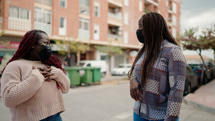 Two african american friends wearing medical mask standing together at street