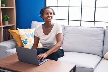 Middle age african american woman using laptop sitting on sofa at home