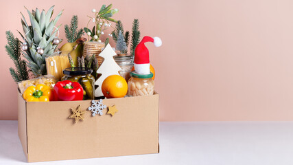 Canned food, pasta, fruits and vegetables in a box for donation decorated for Christmas, charity...