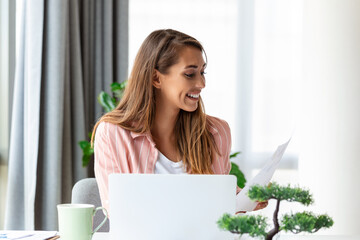 Focused business woman using laptop at home, looking at screen, chatting, reading or writing email, sitting on couch, female student doing homework, working on research project online