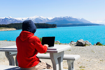 Digital nomad freelancer man as running remotely with bright scenic view of lake as winter mountain