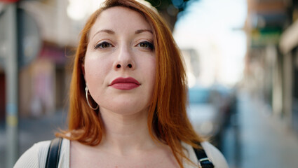 Young redhead woman with relaxed expression standing at street