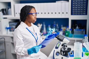 African american woman wearing scientist uniform working laboratory