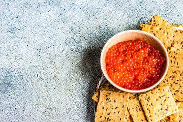 Bowl of red trout fish caviar with flax and sesame seed crackers