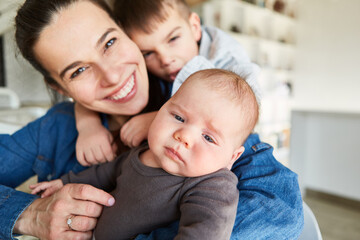 Happy smiling mother with baby and big brother