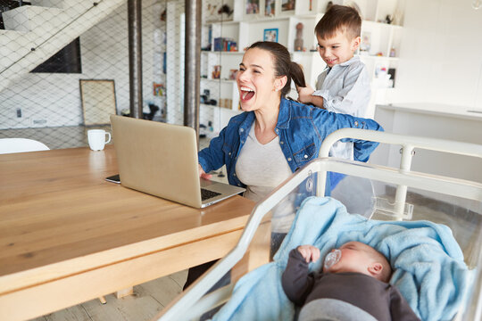Mother at the PC in the home office is disturbed by the child