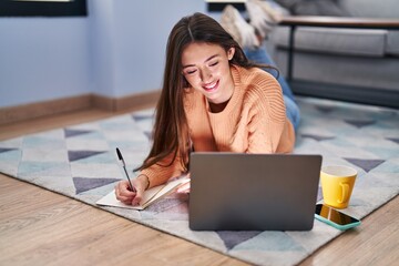 Young beautiful hispanic woman lying on floor studying at home - Powered by Adobe