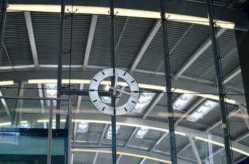 Beautiful modern clock hanging on big glass indoors