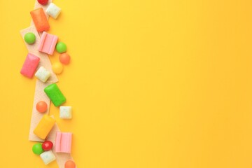 Many different chewing gums on yellow background, flat lay. Space for text