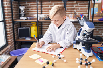 Adorable toddler student smiling confident writing on notebook at classroom