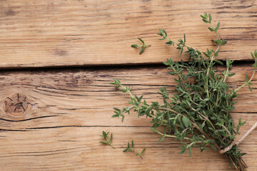 Bunch of fresh thyme on wooden table, top view. Space for text