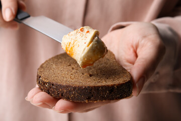 Woman spreading delicious hummus onto bread, closeup