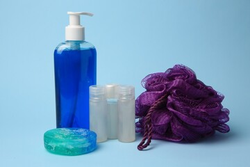Obraz na płótnie Canvas Purple shower puff and cosmetic products on light blue background