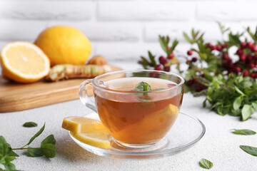 Glass cup of delicious immunity boosting tea with ingredients on light grey table