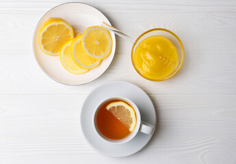 Cup with delicious immunity boosting tea, lemon and honey on white wooden table, flat lay