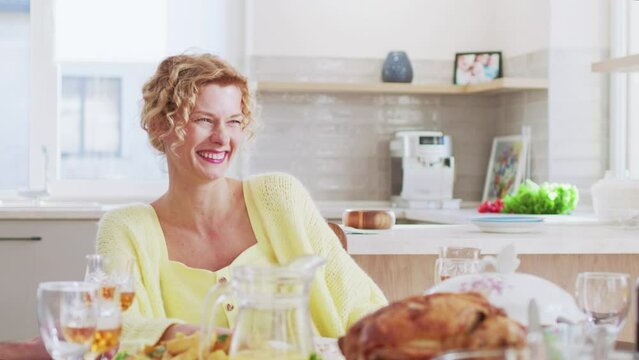 Portrait of happy beautiful young woman having family breakfast with family raising toast eating delicious food. Group of cheerful people celebrating at home. Family life concept.